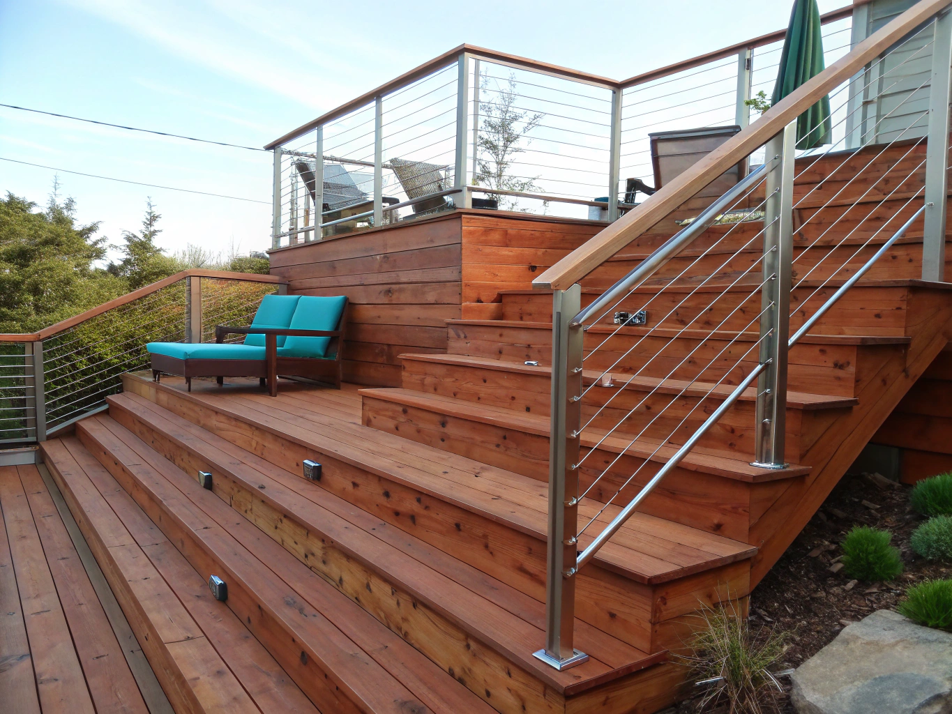 Custom multi-level cedar deck with sleek aluminum railings overlooking a wooded backyard